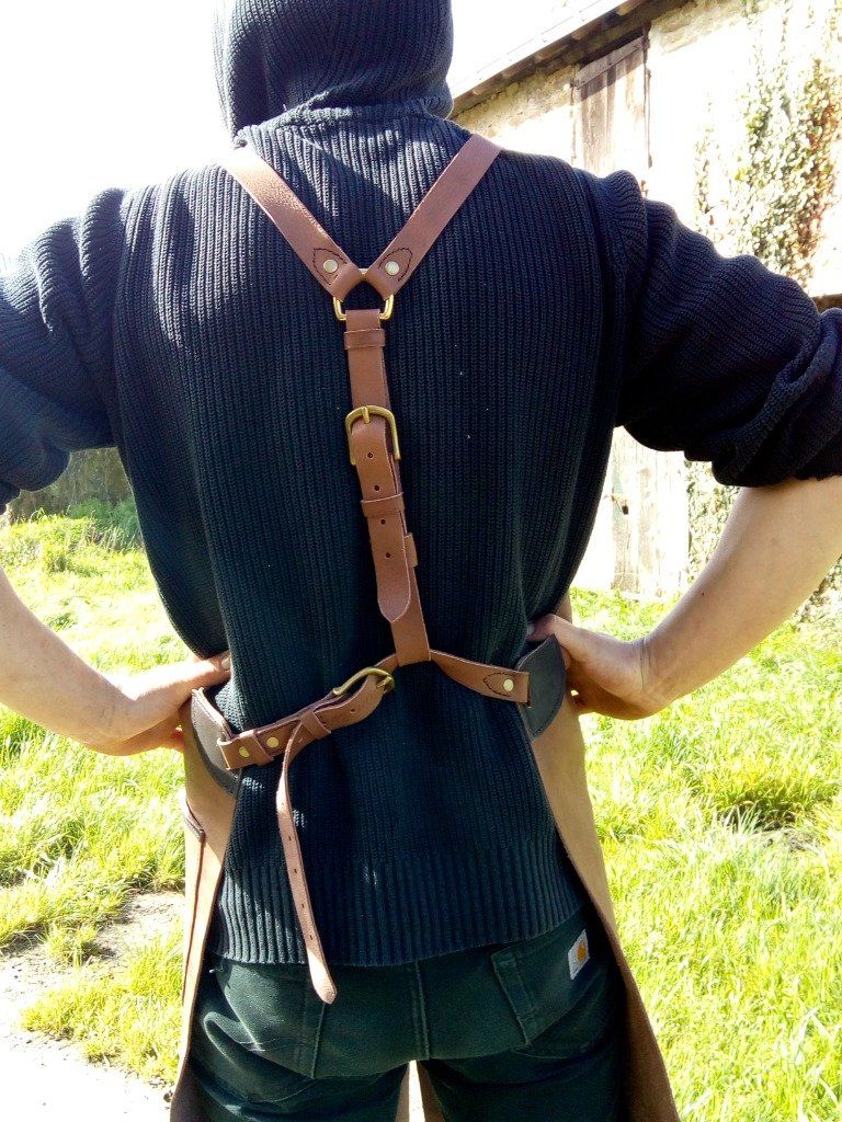 Tablier de forge, en cuir : bretelles croisées pour soulager les épaules et ceinture de maintien à la taille.